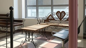 Un'area salotto interna illuminata dal sole, con una panca di legno, un tavolo e una sedia in metallo.