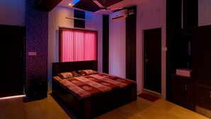 A bedroom with a bed, a ceiling fan, an air conditioning unit, and a window with curtains. - Hotel Geeta Bhawan (Karnaprayag)