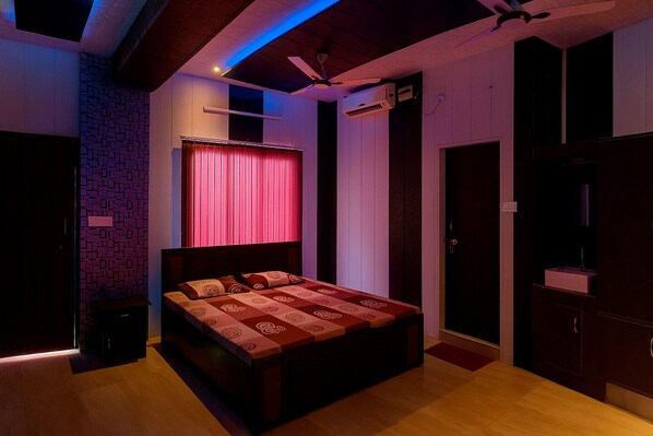 Une chambre à coucher avec un lit, un ventilateur de plafond, un appareil de climatisation et une fenêtre avec des rideaux.