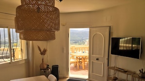 A modern living room with a dining area, a television, and a view of the outdoors. - Villa Almazara (Xalo)