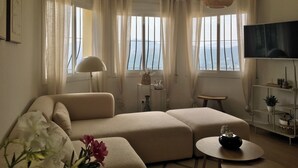 A living room with a sofa, a small table, a lamp, and a TV. - Villa Almazara (Xalo)