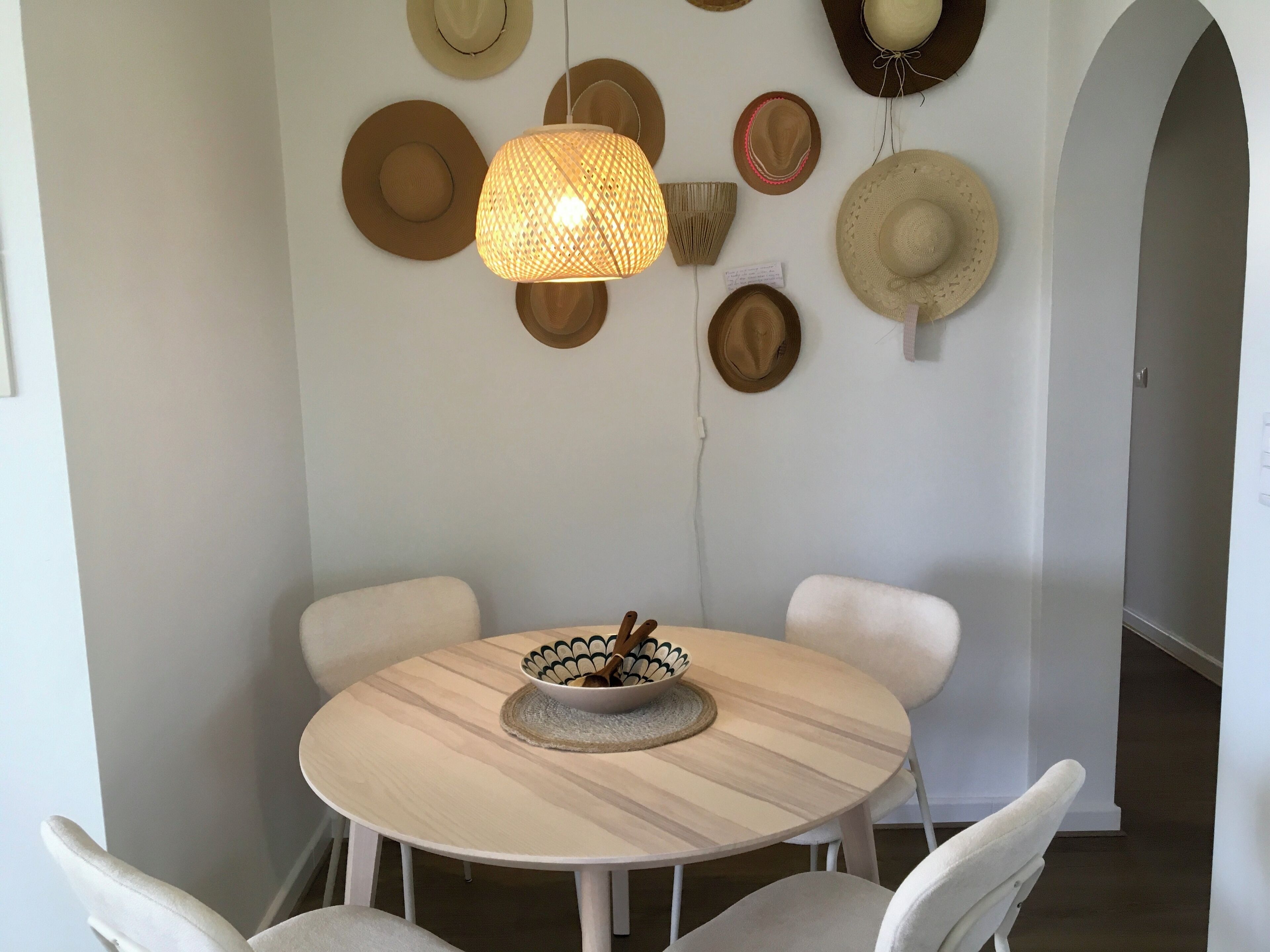 Un espace repas avec une table ronde, des chaises blanches et un luminaire suspendu.