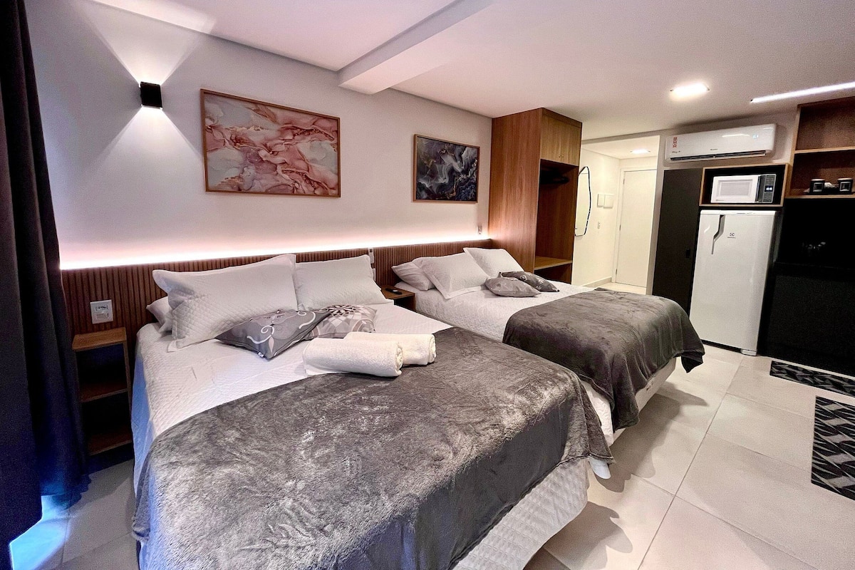 A modern hotel room with two beds, a microwave, a refrigerator, and artwork on the walls.