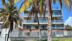 A multi-story hotel with balconies, a stone facade, and palm trees. - Hyde Park Select - by Living (Joao Pessoa)