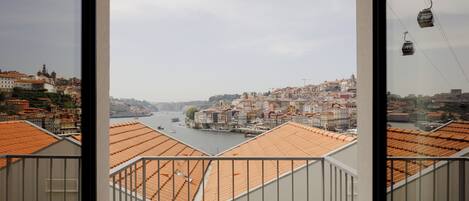 A view from a balcony with a river and historic buildings in the background.