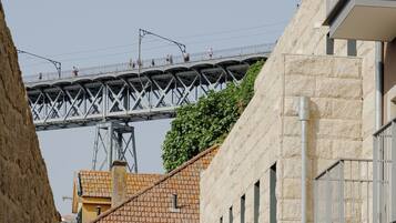 A bridge with people walking on it, a building with a stone facade, and a tree in the foreground.
