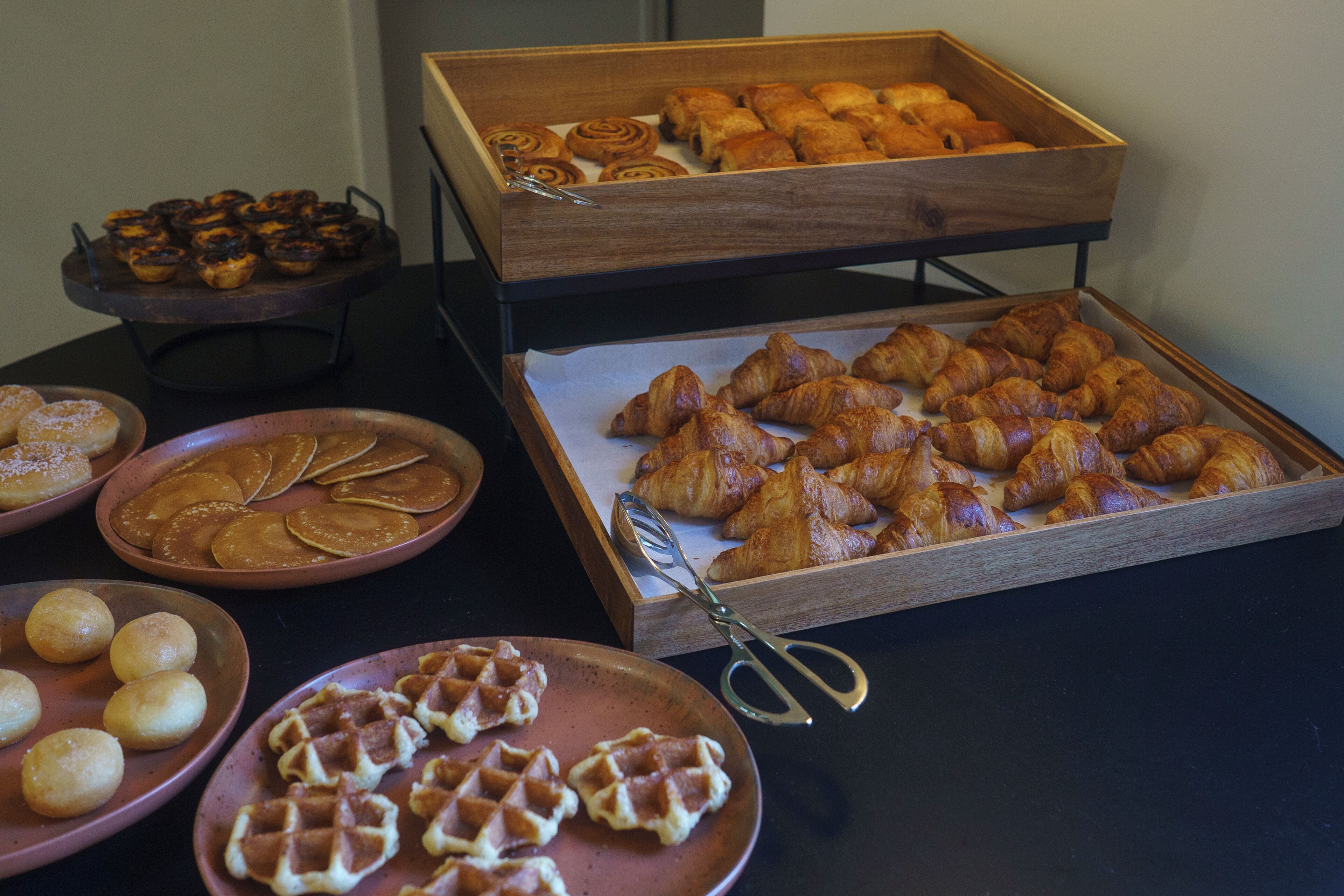 Un buffet proposant une variété de produits de boulangerie, notamment des gaufres, des pâtisseries et des croissants.