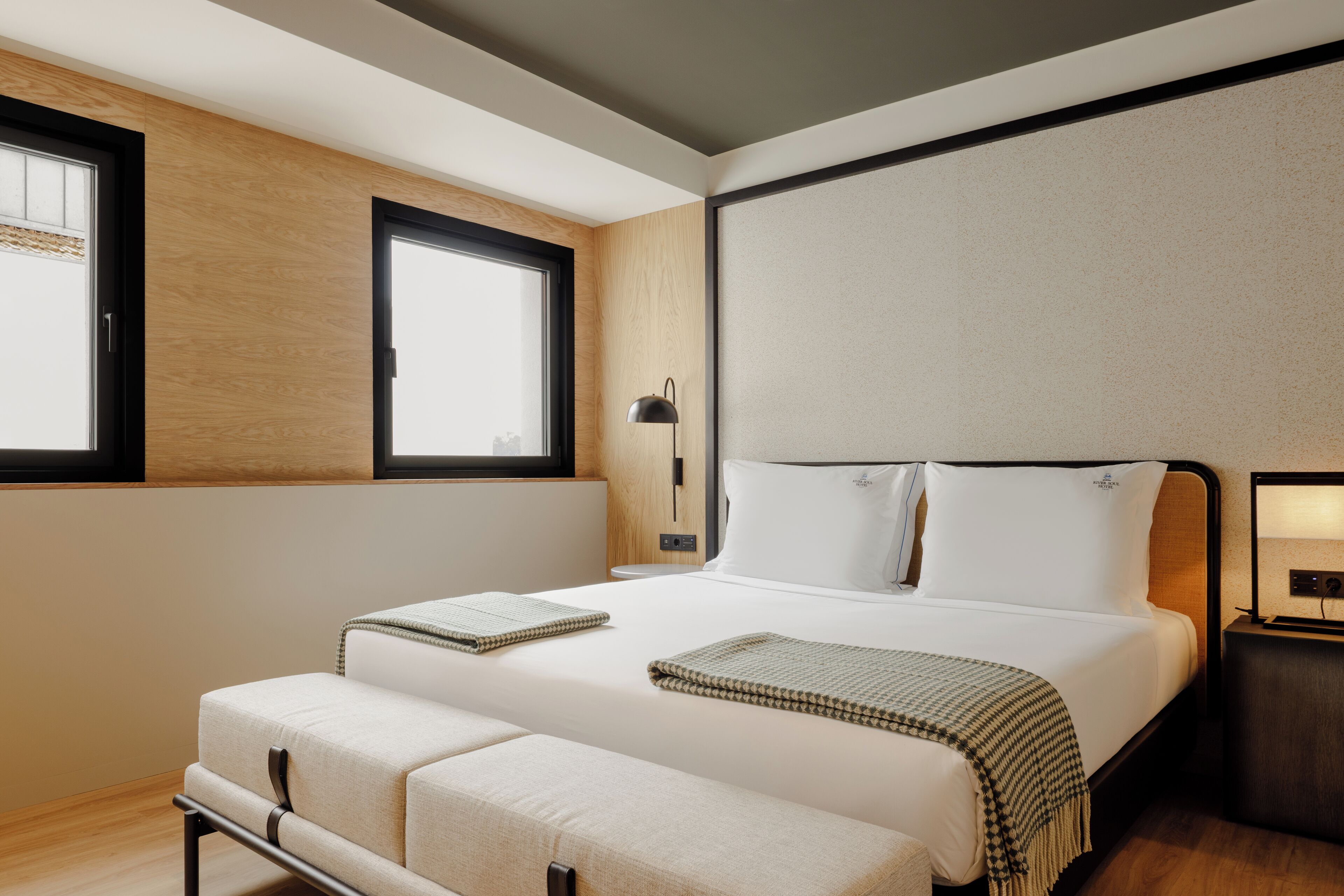 Una habitación de hotel moderna con una cama grande, mesitas de noche y una ventana.