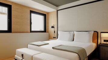 Una habitación de hotel moderna con una cama grande, mesitas de noche y una ventana.
