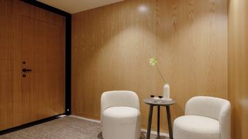 Ein Zimmer mit einer Holzwand, einer Tür, zwei weißen Stühlen und einem kleinen runden Tisch mit einer Vase und zwei Gläsern.