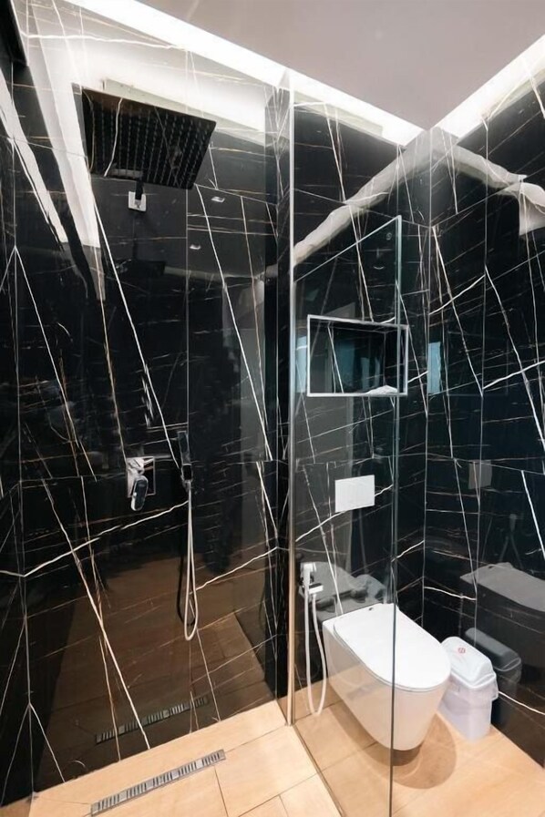 A modern bathroom with black marble walls, a glass-enclosed shower, and a white bathtub. - Day LUX Premium Apartments (Sarandë)