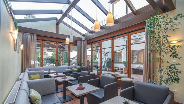 A modern outdoor seating area with sofas, tables, and potted plants. - DEVA Hotel Renchtalblick (Oberkirch)