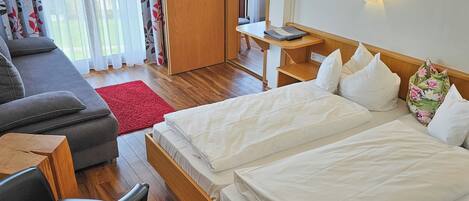 Ein Hotelzimmer mit einem Bett, einem Schreibtisch, einem Sessel, einer Couch und einem roten Teppich.