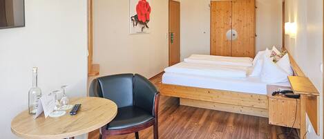 Una habitación de hotel con una cama, una silla, una mesa con control remoto y un teléfono.