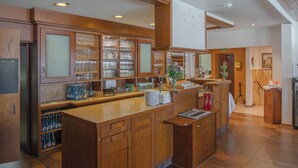 A spacious kitchen with wooden cabinetry, a central island, and a tiled floor. - DEVA Hotel Renchtalblick (Oberkirch)