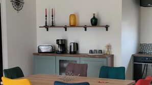 A modern kitchen with a wooden table, colorful chairs, and a mounted TV.
