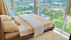 A bedroom with a large bed, a view of a cityscape through large windows, and a city view from the window. - 180° Manila View near Airport, MOA, PICC and World Trade Center w/ Massage chair (Pasay City)
