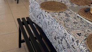 A kitchen with white cabinets, a microwave, a toaster, and a refrigerator. There is a dining table with a patterned tablecloth and woven placemats. - Oceanfront 2 bedroom house with WiFi in Freeport on 45 acres. (Freeport)