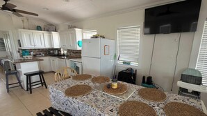 A kitchen with white cabinets, a refrigerator, a microwave, and a dining table with placemats. - Oceanfront 2 bedroom house with WiFi in Freeport on 45 acres. (Freeport)