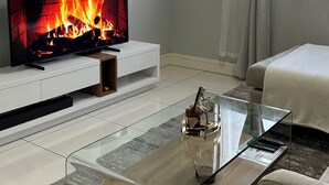 Una sala de estar moderna con un televisor de pantalla plana, una mesa de centro de vidrio y un sofá.