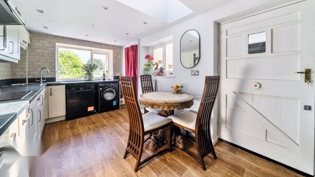 A modern kitchen with a dishwasher, a sink, and a window. There is a dining area with a round table and chairs. - 4/5 Bed-2 Bath-bar-pool Table-library-parking For7 (Dorchester)