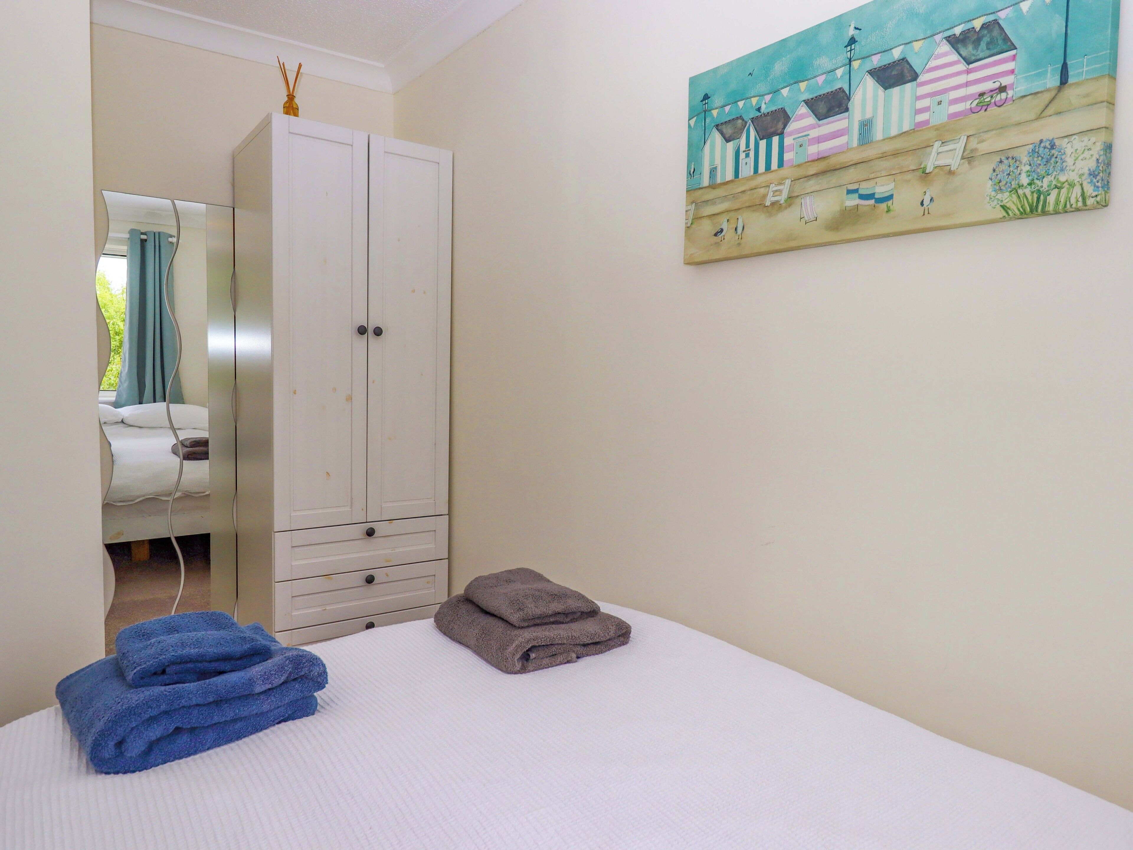 Un dormitorio con cama, armario y un cuadro en la pared.