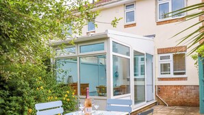 A patio with a table and chairs, a bottle of wine, and a glass. - Hedgehogs (Barnstaple)