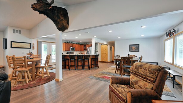 A spacious living room with a large wooden dining table, a comfortable sofa, and a bull head mounted on the ceiling. - Newly renovated large space - great for groups (Hayward)
