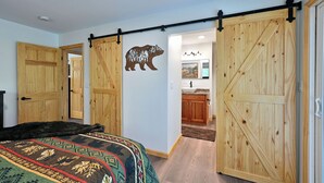 A bedroom with a large bed, wooden wardrobe, and a sliding barn door. - Newly renovated large space - great for groups (Hayward)