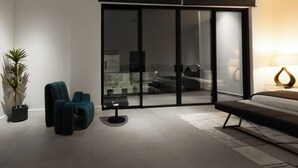 A modern living room with a sofa, two armchairs, a coffee table, and a potted plant. - The VVS Apartments - Penthouse Apartment (Accra)