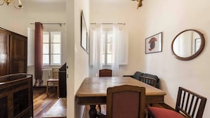 A dining area with a wooden table, chairs, and a chandelier. There are windows with curtains and a radiator. - Ghibellina Retreat by MMega (Florence)