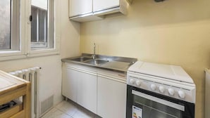 A compact kitchen with white cabinets, a stainless steel sink, and a white stove. - Ghibellina Retreat by MMega (Florence)