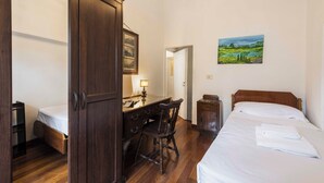A bedroom with a wooden wardrobe, a desk with a chair, a bed with white linens, and a landscape painting on the wall. - Ghibellina Retreat by MMega (Florence)