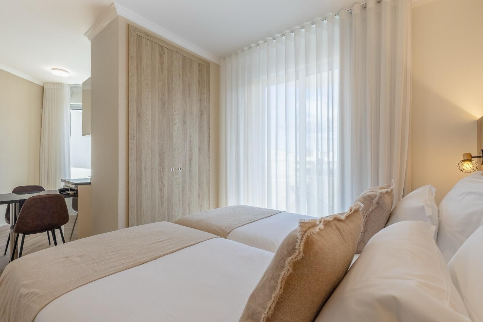 Ein Hotelzimmer mit zwei Betten, einem Schreibtisch und einem Stuhl.