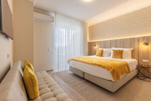 A modern bedroom with a large bed, a sofa, and a small side table.