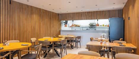 A modern dining area with wooden panel walls, multiple round tables, and chairs.