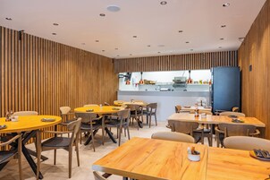 A modern dining area with wooden panel walls, multiple round tables, and chairs.