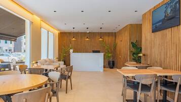 A modern hotel lobby with a reception desk, seating area, and large windows.