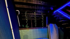 A hot tub with a wooden exterior, surrounded by a blue wall and a white table with a floral arrangement.