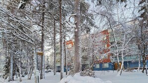 A snow-covered outdoor area with trees and a building in the background. - Spacious apartment with balcony and free WiFi (Rovaniemi)