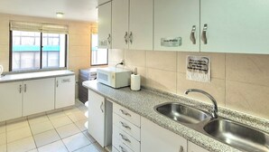 Una cocina moderna con armarios blancos, un lavamanos de acero inoxidable y una ventana con vistas.