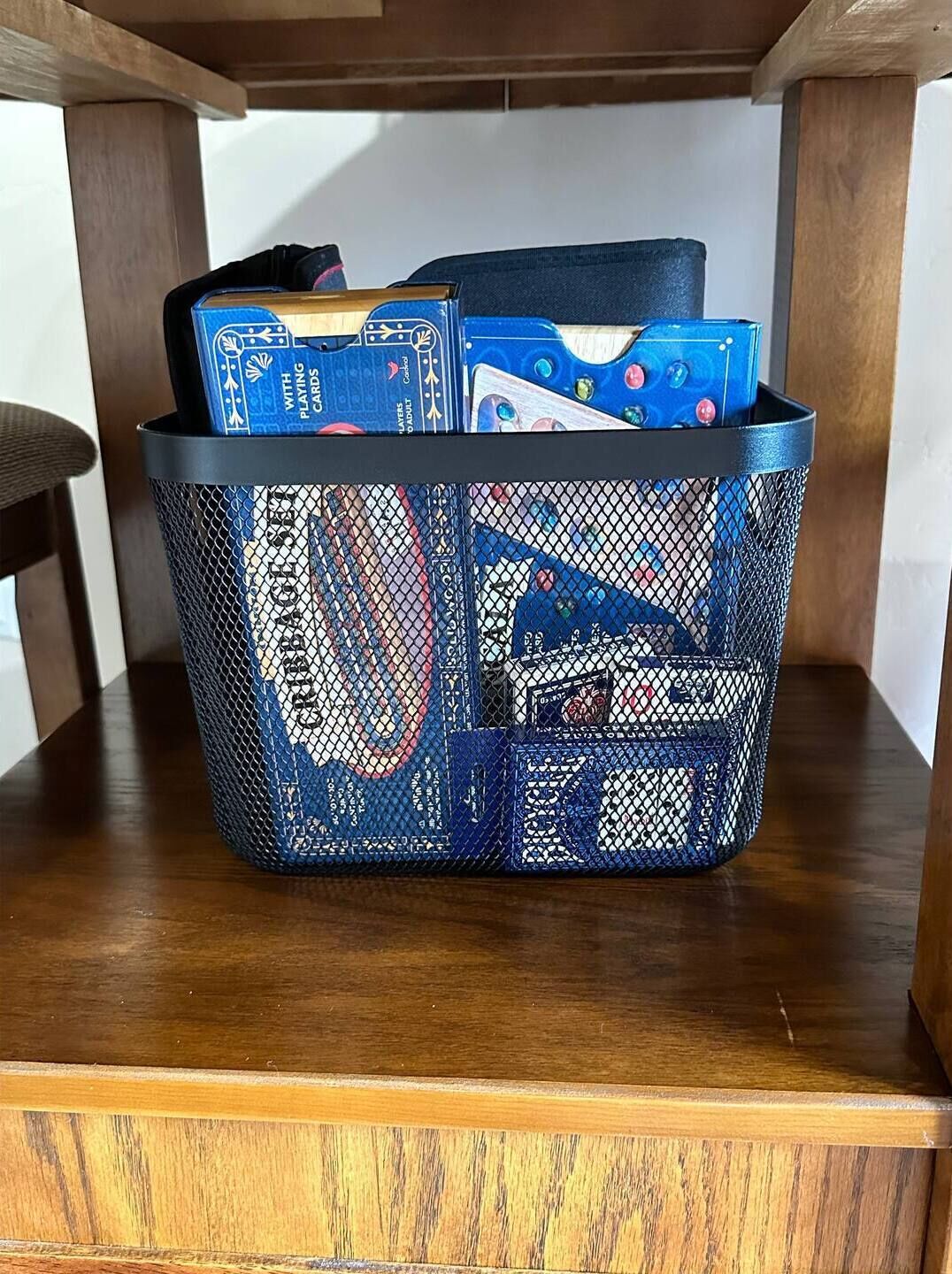 Un panier bleu à motifs en maille, rempli de divers objets, posé sur une surface en bois.