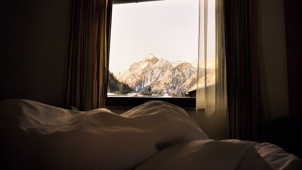 Habitación de hotel con cama y ventana que ofrece vistas a la montaña.