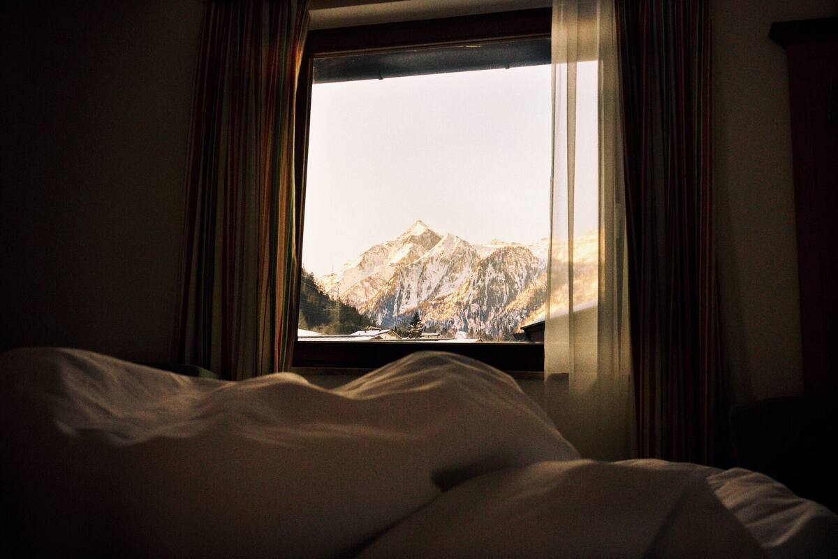 A hotel room with a bed and a window offering a mountain view.