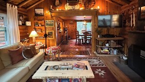 A cozy log cabin interior with a living room, dining area, and a TV.
