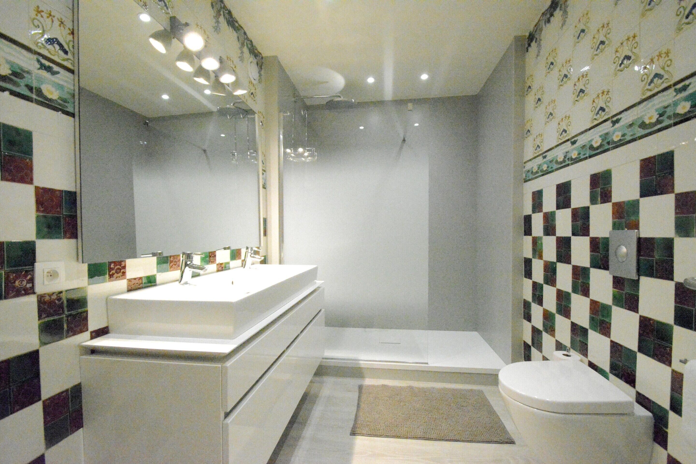 A bathroom with a white sink, a bathtub, and a toilet. The walls have a checkered tile pattern.