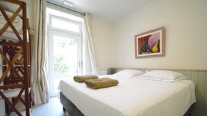 A hotel room with a bed, a wooden ladder, a door with curtains, and a wall with a framed picture. - Holiday Home in Bouillon Near River Semois (Bouillon)