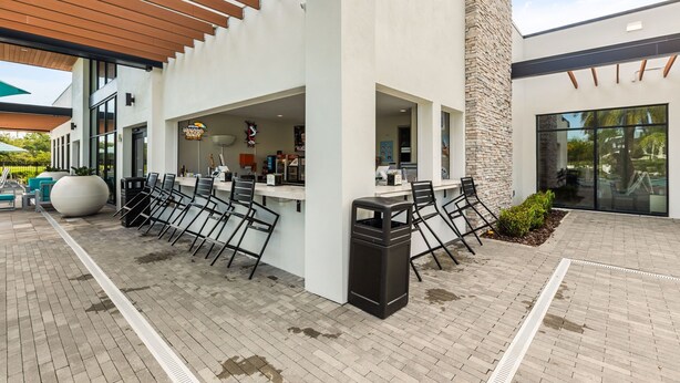 Un espace extérieur aménagé avec un bar, des chaises et une poubelle.