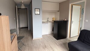 Un espacio habitable compacto con kitchenette, comedor y zona de estar.