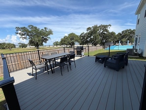 Une terrasse avec une table et des chaises, un barbecue et une vue sur une piscine.